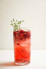 Christmas cocktail with berries and thyme on the rustic background. Selective focus.