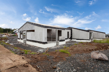 Fototapeta na wymiar Construction of building of new white concrete houses with .incomplete wooden roof