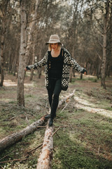 Woman in casual clothes walking on a fallen tree trunk in the forest.