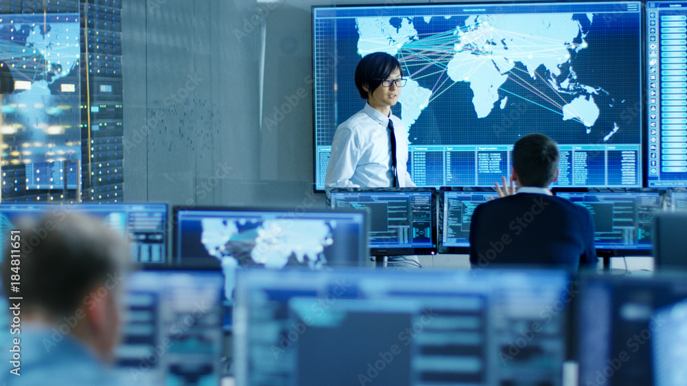 Leinwandbilder In the System Control Room Manager Holds a Briefing for His Staff Members. They're Work in Data Center and are Surrounded by Multiple Screens Showing Maps, Logistics Data.
