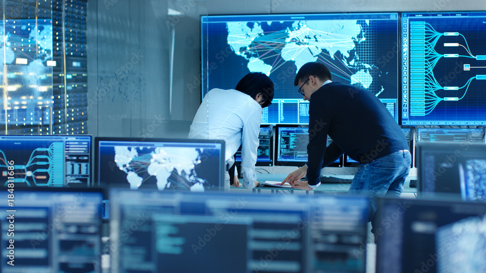 Aufkleber In the System Control Room Project Manage and IT Engineer Have Discussion, they're surrounded by Multiple Monitors with Graphics. Big Monitor Shows Interactive Logistics Map.