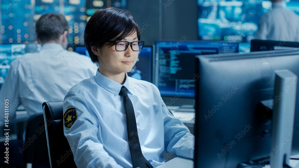 Poster in the security command center officer at his workstation monitors multiple screens for unlawful inf