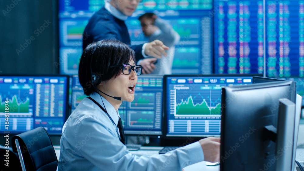 Poster In the Network Operations Senior Trader Dictates Stock Numbers to Their Operator who Makes Call with a Headset. In the Background Traders Discuss Data Shown on Monitors.