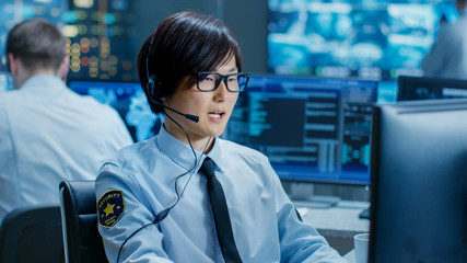 In the Security Command Center Officer at His Workstation Monitors Screens and Communicates with...