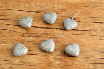 Valentines day. Six silver hearts isolated against a wooden background
