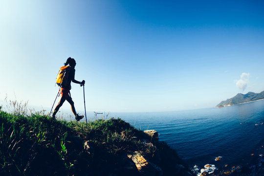 Young woman hiker hiking on sunrise seaside