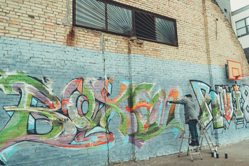 low section view of man painting colorful graffiti on building