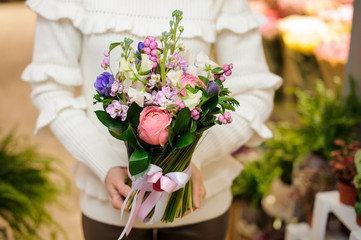 Woman dressed in a white sweater holding a pretty flower bouquet for Valentine's day