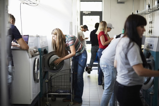 Multi-ethnic university students using washing machines in laundromat