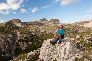 Young female is enjoying sunshine in Dolomite mountains, Italy
