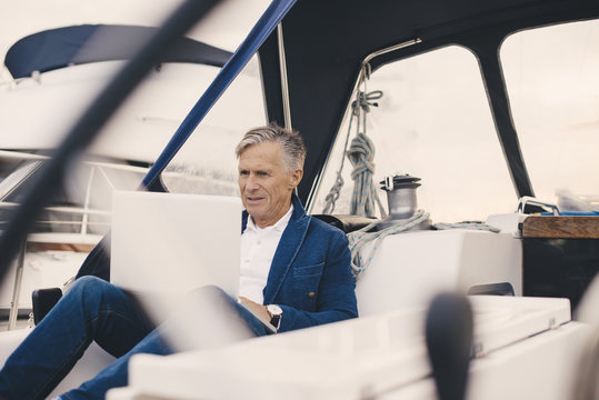 Senior man using laptop on yacht