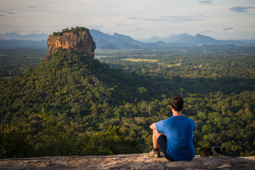 Naklejka na ściany i meble Young man looking at the Sigiriya Rock from Pidurangala rock in Sri Lanka