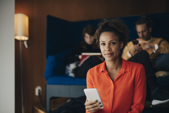 Portrait of businesswoman using smartphone in office cafeteria