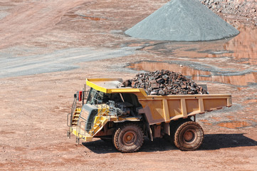 dumper truck carrying porphyry rocks through a quarry mine.