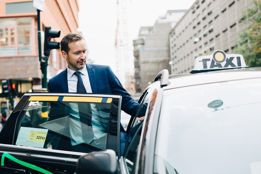 Mature businessman entering taxi in city