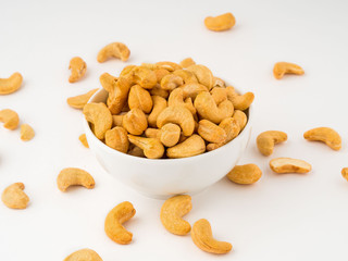 white bowl with a handful of nuts of cashew on white background table