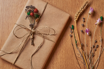 Book wrapped in brown paper, tied with paper thread lying on the tabletop near dry plants.