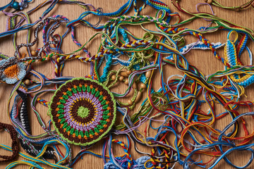 Different kind of knitted colorful bracelets and earrings are chaotically lying on the table. In the lower left side there is a big knitted amulet.