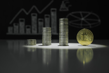 Stacks of crypto currency and gold bitcoin on the background of charts of crypto currency