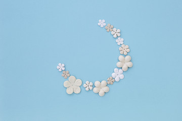 White paper flower arrange in half moon shape on blue paper texture background