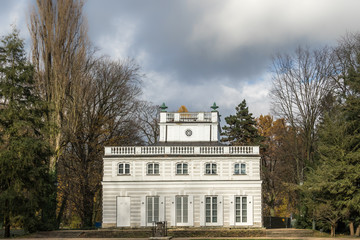 Little White House built by Domenico Merlini in 1774-76 among bare trees under the dramatic cloudy sky. Royal Baths Park, Warsaw, Poland
