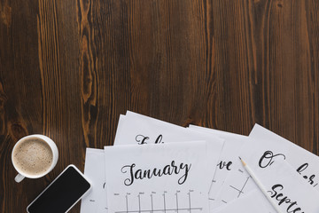 flat lay with paper calendar papers, smartphone and cup of coffee on wooden tabletop