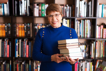 Happy senior woman  with books in library.