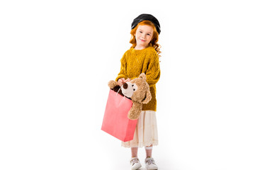 red hair child holding teddy bear in shopping bag isolated on white
