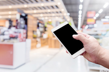 MAN HAND SMARTPHONE WITH blur background image of shopping mall or department store with bokeh and people background usage concept