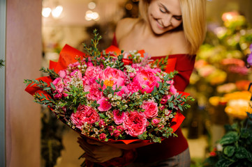 Smiling blonde girl with a large and bright bouquet of flowers for the Valentine s day