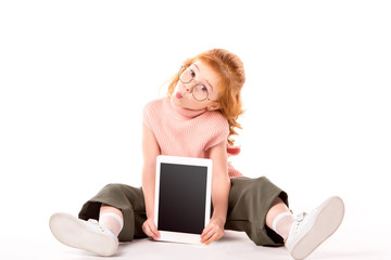 kid with ginger hair sitting and showing tablet on white