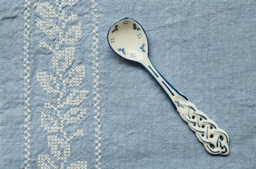 Spoon with a blue pattern on the background of a blue tablecloth with embroidery on a wooden background