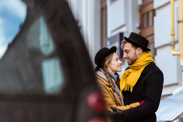young attractive couple hugging behind car