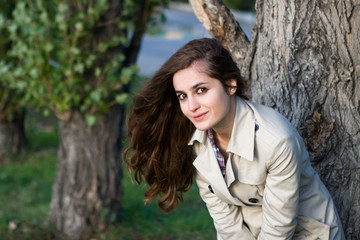 Young beautiful woman wearing beige jacket standing over the tree park background