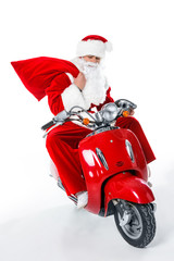 Santa Claus with big red bag sitting on red scooter, isolated on white