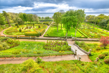 Panorama of the green gardens of Dunrobin Castle with fountains hedges and secular trees in Scotland, United Kingdom. Scottish Highlands, UK. Top aerial view.