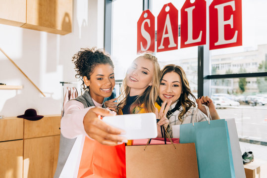group of happy young women taking selfie on shopping