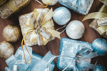 Top view image of golden and silver present boxes and Christmas decorations on wooden background
