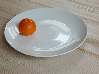 Bright orange satsuma on a white plate on a table