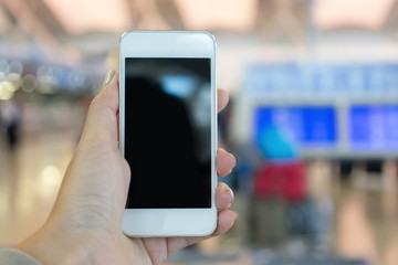 Woman holding smart phone on airport for checking flights.