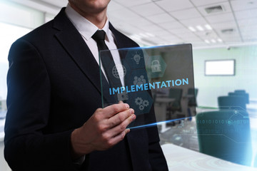 Business, Technology, Internet and network concept. Young businessman working on a virtual screen of the future and sees the inscription: Implementation