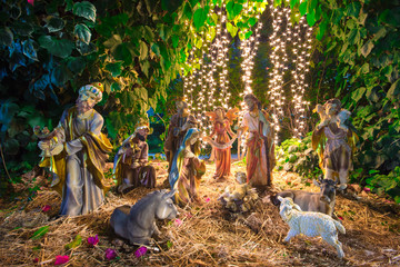 Christmas Manger scene with figurines including Jesus, Mary, Joseph, sheep, magi and lights.