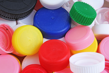 Collect plastic bottle caps. Close-up shot of stack of recyclable plastic bottle caps on white background. Bottle cap texture pattern as background. Colorful plastic cap.