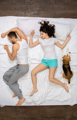 Young couple relaxation on the bed top view with a dog sleeping