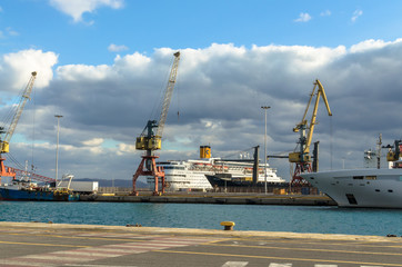 Fototapeta premium Heraklion, Crete, Greece - November, 2017: In the foreground - sea and pier of the port of Heraklion, loading equipment, cruise liner, cars, in the background - mountains