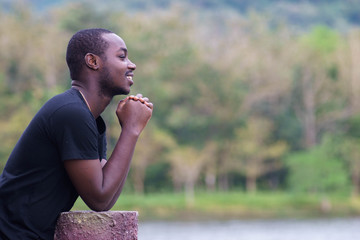African man praying at the park.