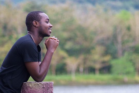 African man praying at the park.