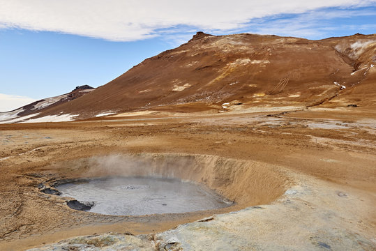 A thermal hot spring boils in a burnt orange landscape at Námaskarð or Namaskard in Iceland.