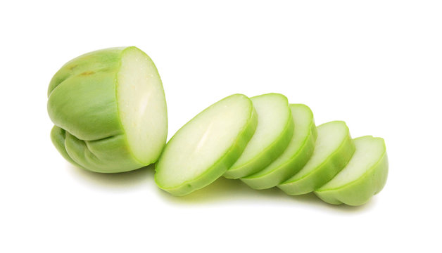 A chayote squash that has been cut in half on a white background.