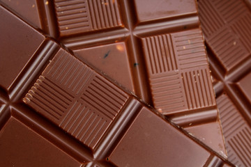 Chocolate bars as background. Milk and dark shiny chocolate texture. Stack chocolates pattern. Stunning beautiful cacao brown dessert sweets.